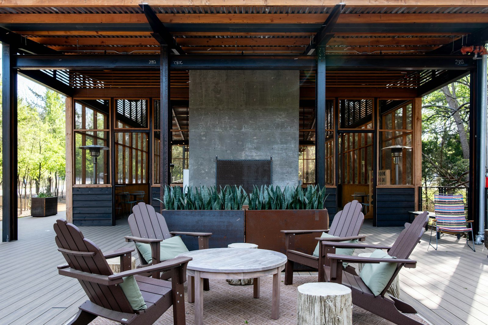 Covered outdoor lounge with sofas and a fireplace wall