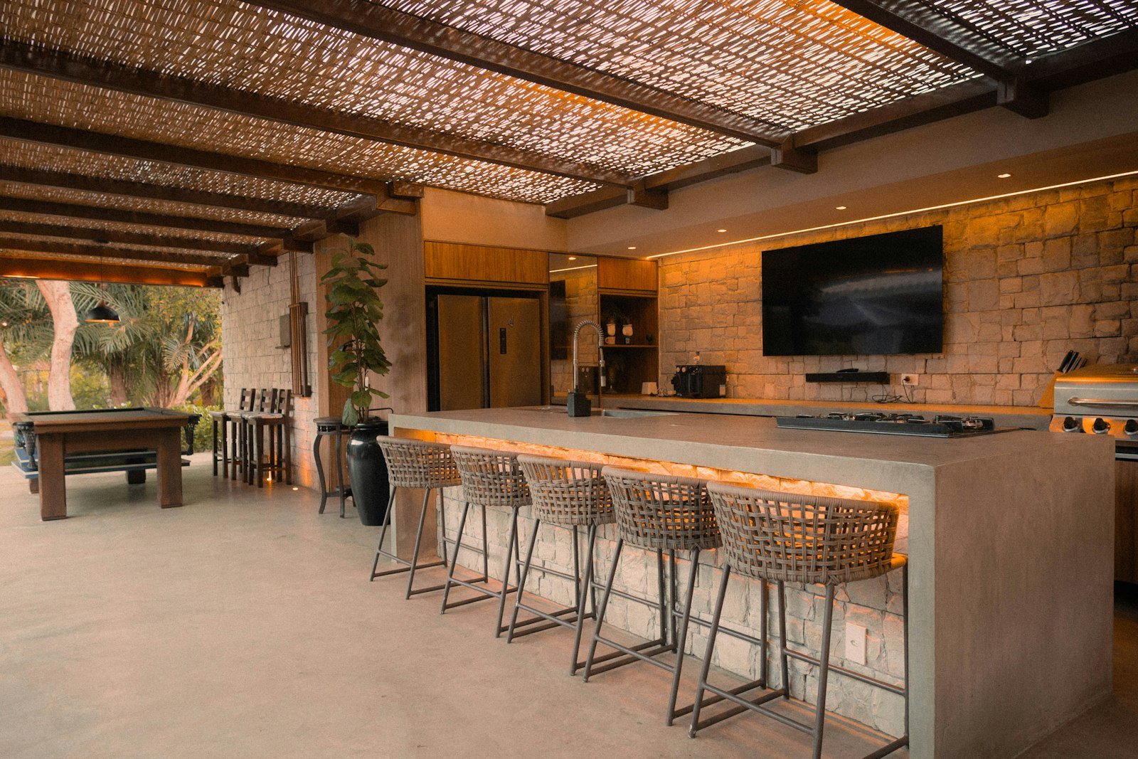 Outdoor kitchen counter with bar stools under a roof
